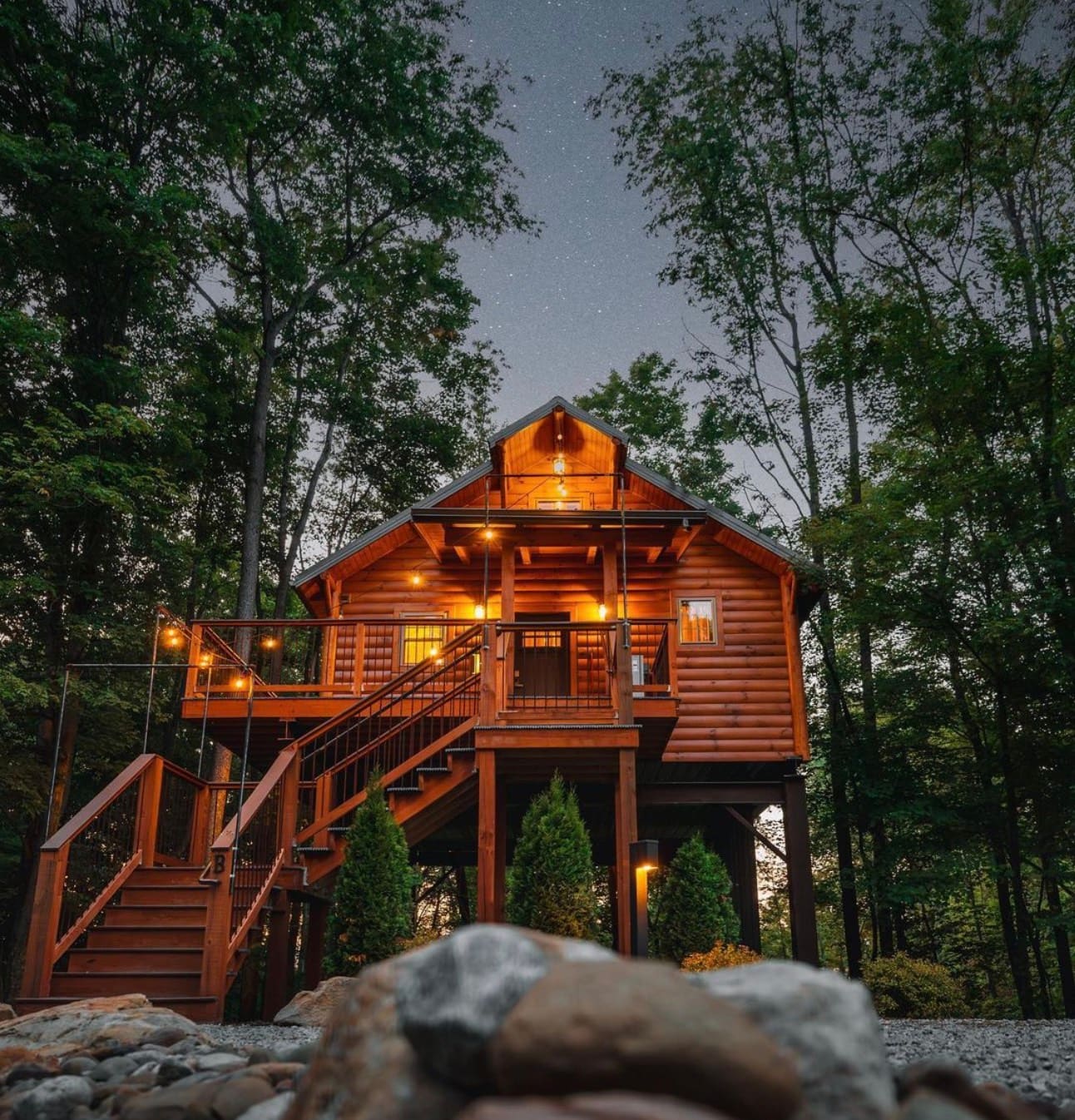 Cricket Hill Treehouse B glowing warmly beneath a starry night sky in Berlin, Ohio