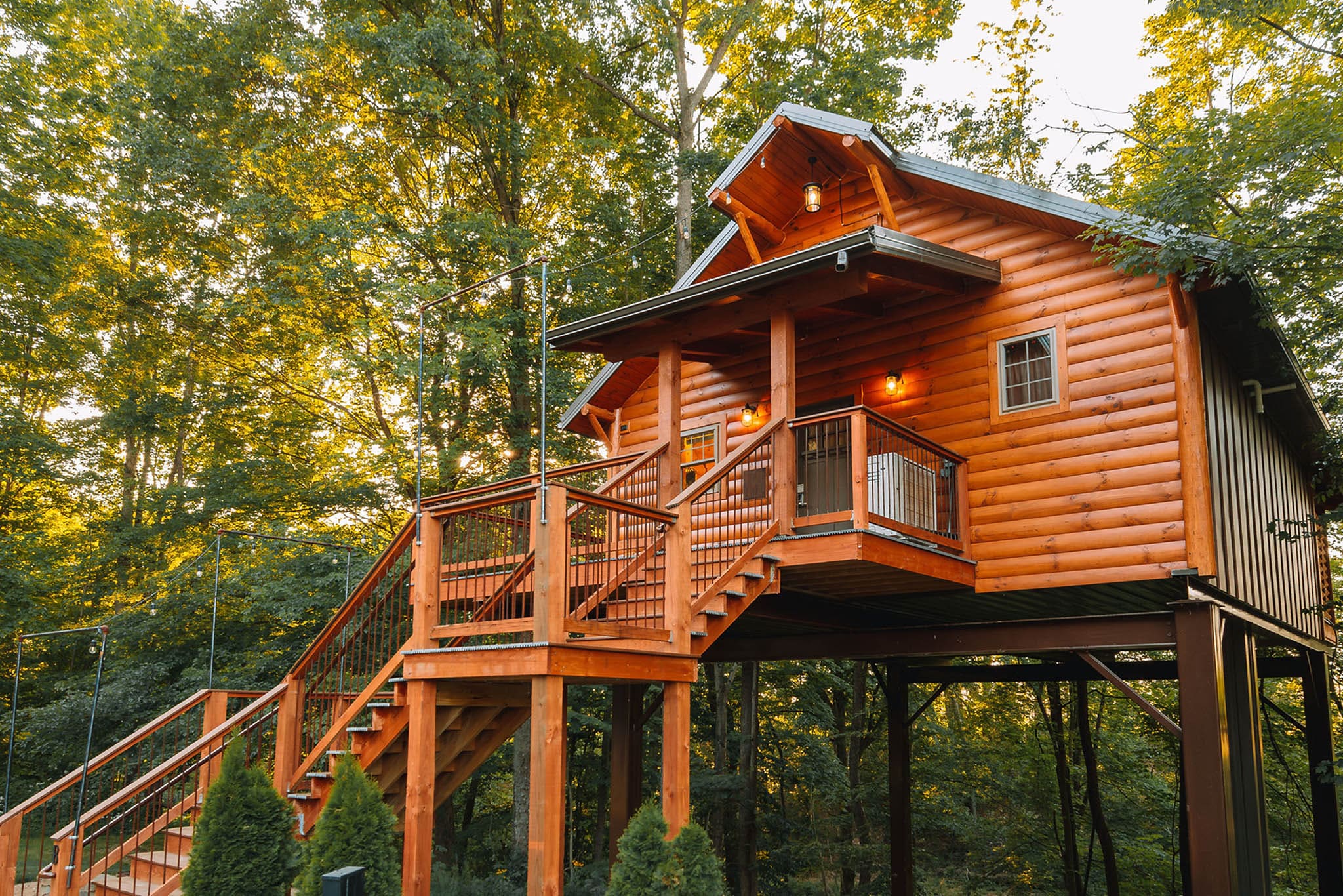 Exterior of Cricket Hill Treehouse C elevated among the trees at golden hour in Berlin, Ohio