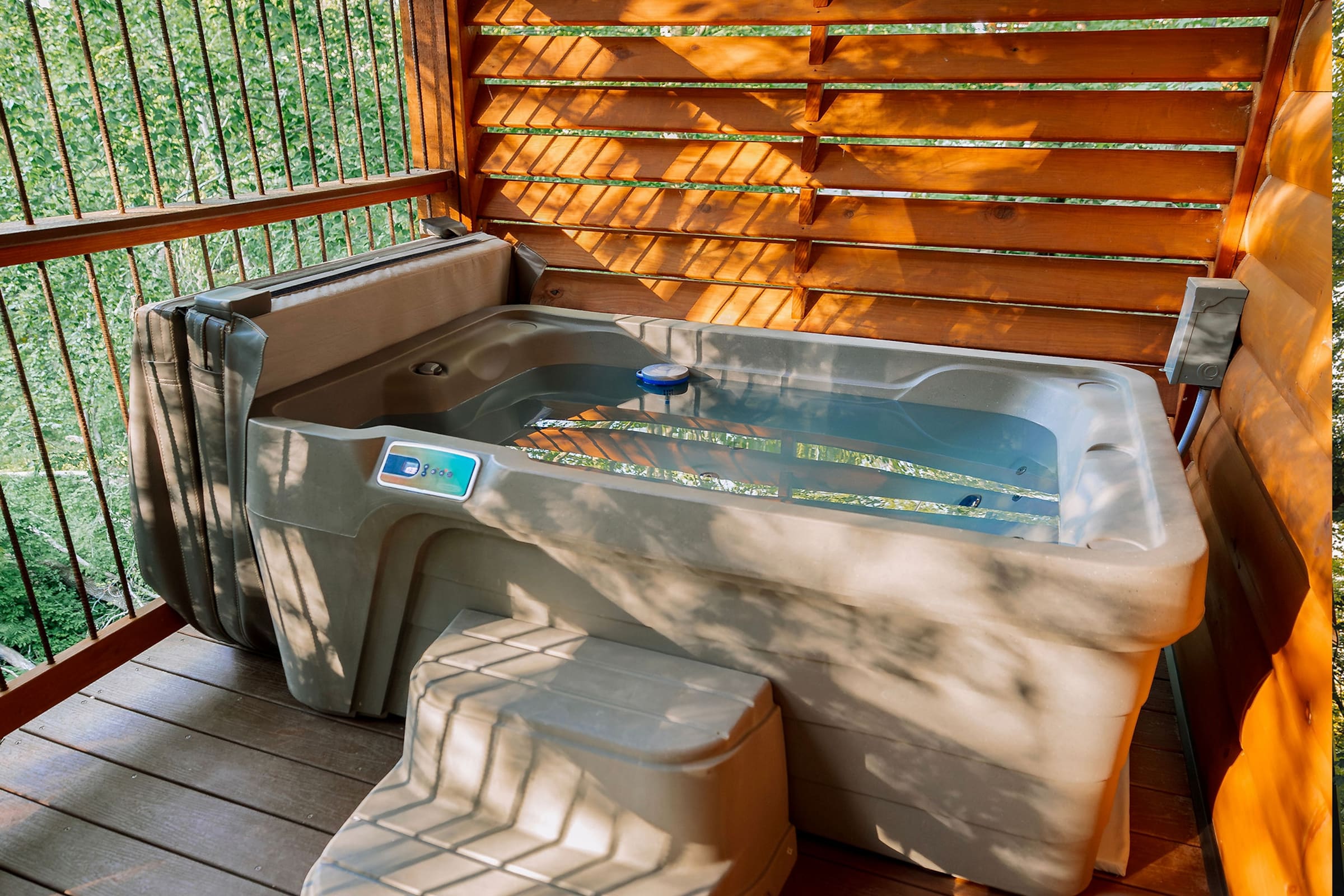 Steaming private hot tub glowing on a Cricket Hill treehouse deck at dusk